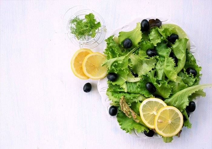 a green salad with black olives dill and lemon