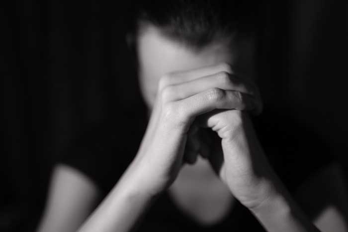 black and white photo of a woman holding her head in stress.