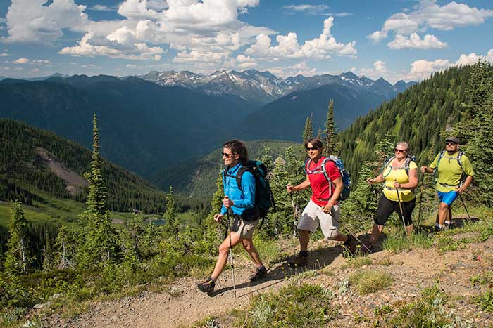 line of 4 adults hiking with poles in beautiful mountain scenery 