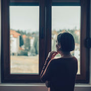 Sad woman looking out of the window in loft apartment