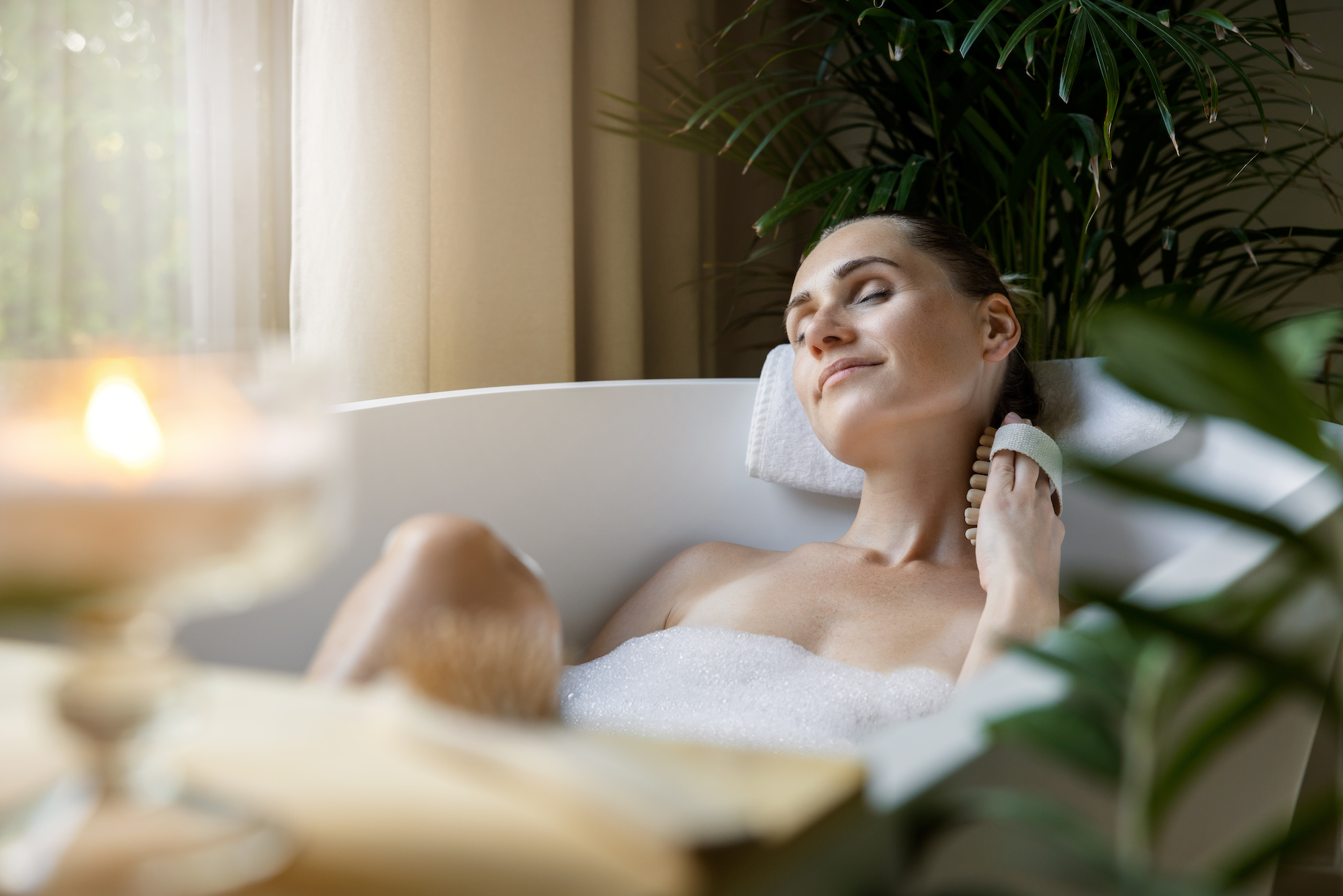 woman enjoying spa bath with foam and body massage brush