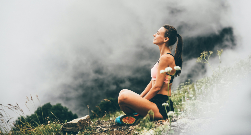 a woman sitting on a hiking trail meditating