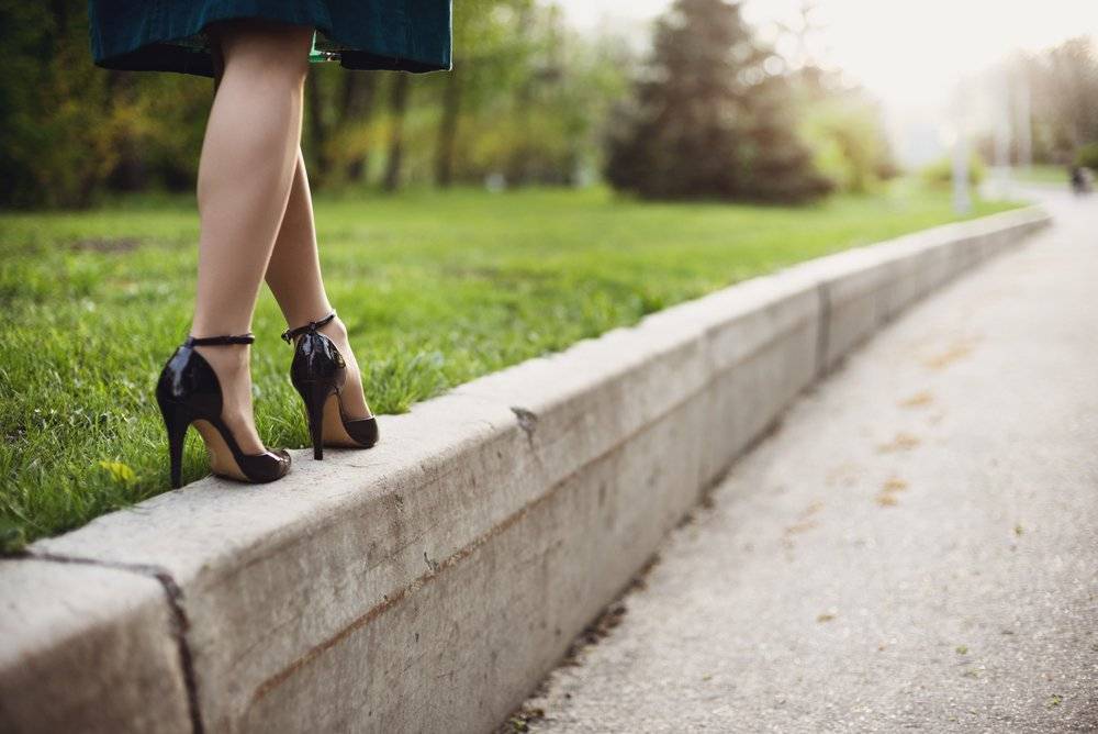 woman in high heels walking along a garden path